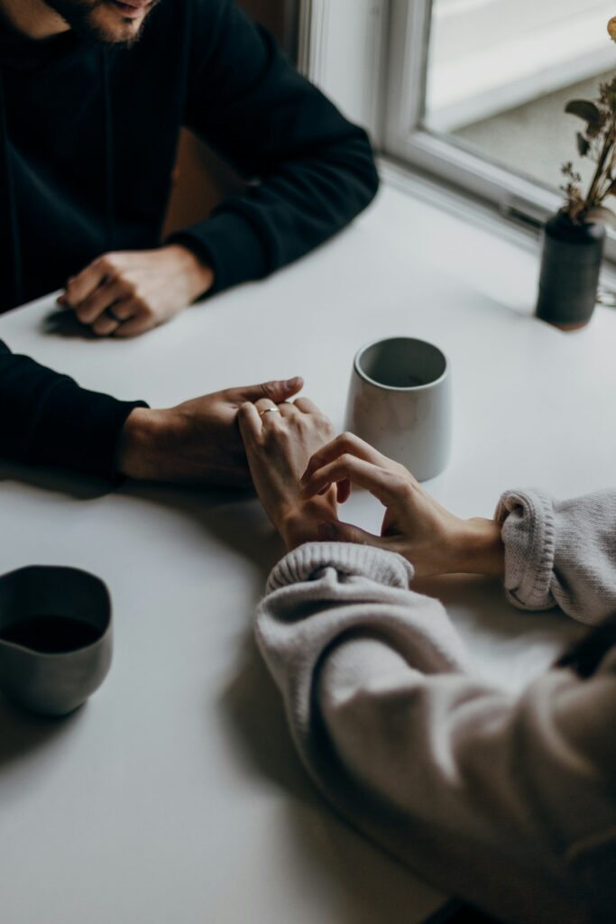 A couple holding hands across a table, a small bid for connection