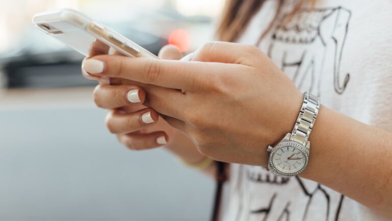 Woman checking her phone for a breadcrumbing text that never becomes a plan