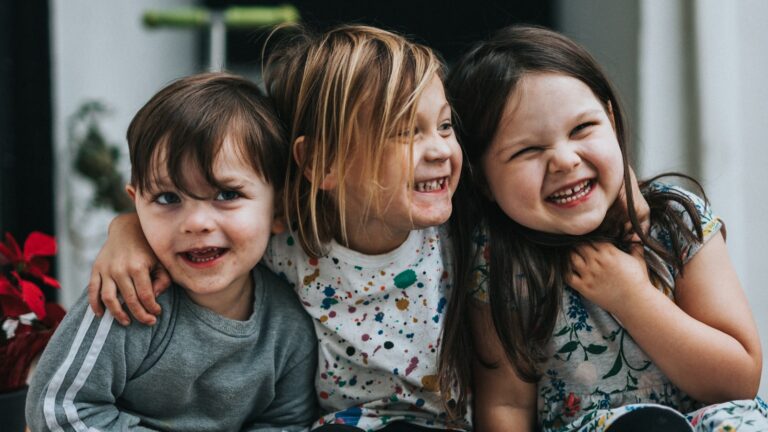 Two siblings sitting together on the floor, an image about parental favoritism between children
