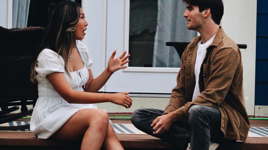 A married couple sitting together on a porch in conversation