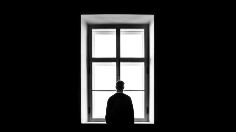 Man standing at a window weighing whether to leave his marriage