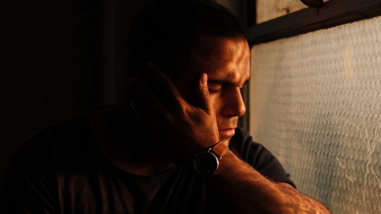 Man resting his head against a window sill thinking about divorce regret