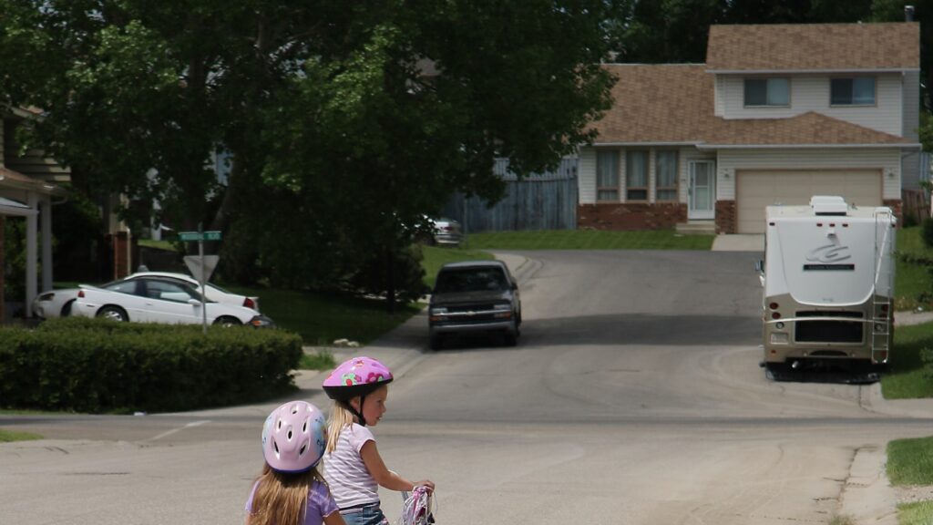 Children riding bikes on a neighborhood street, independent play and childhood anxiety