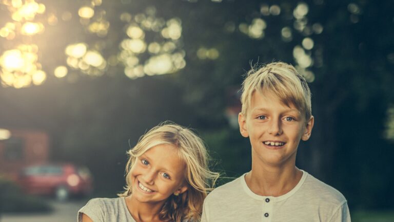 A brother and sister standing together in a field