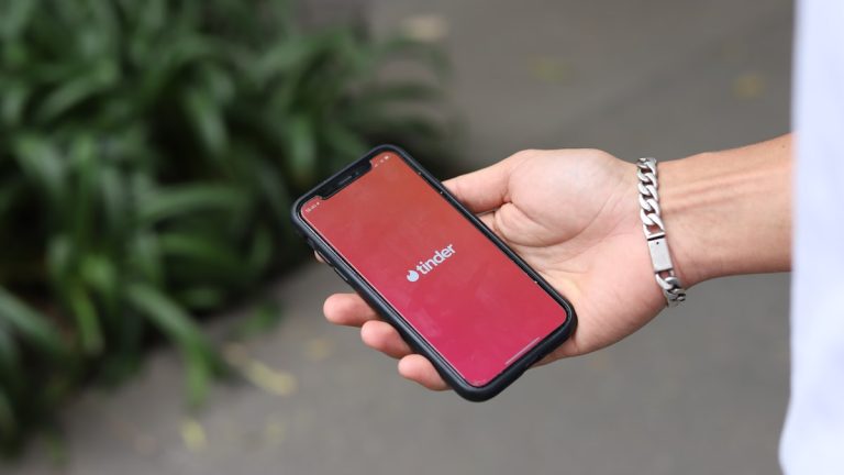 A person feeling dating app fatigue holding a phone