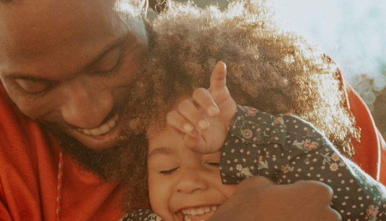 Father using warm, declarative language parenting while connecting with his laughing daughter