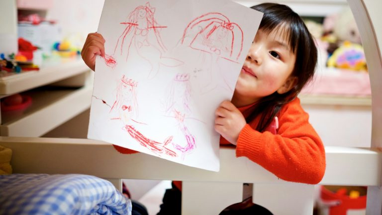 Girl proudly holding up a drawing, a moment to think about how to praise your child