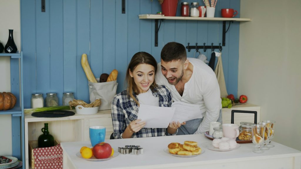 Couple looking over papers together in a bright kitchen, talking through the income gap in relationships