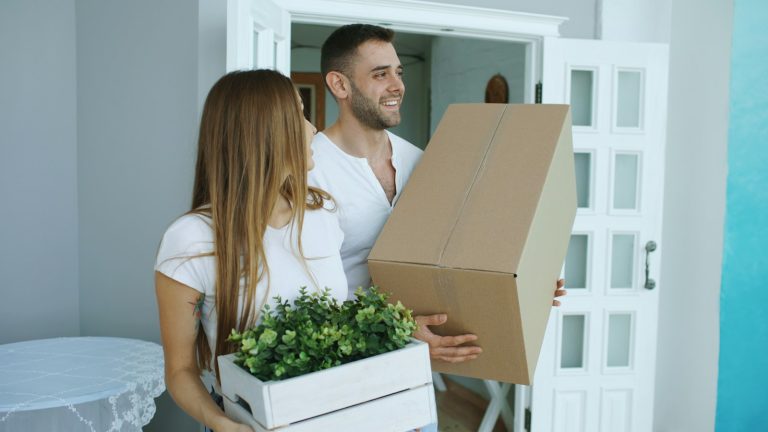 Couple carrying boxes into a new home after moving for your partner