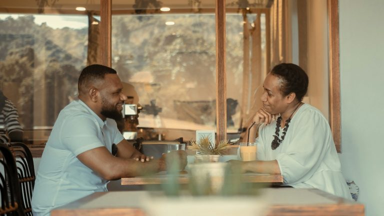 Man and woman sitting at a table talking after a spouse sides with their parents