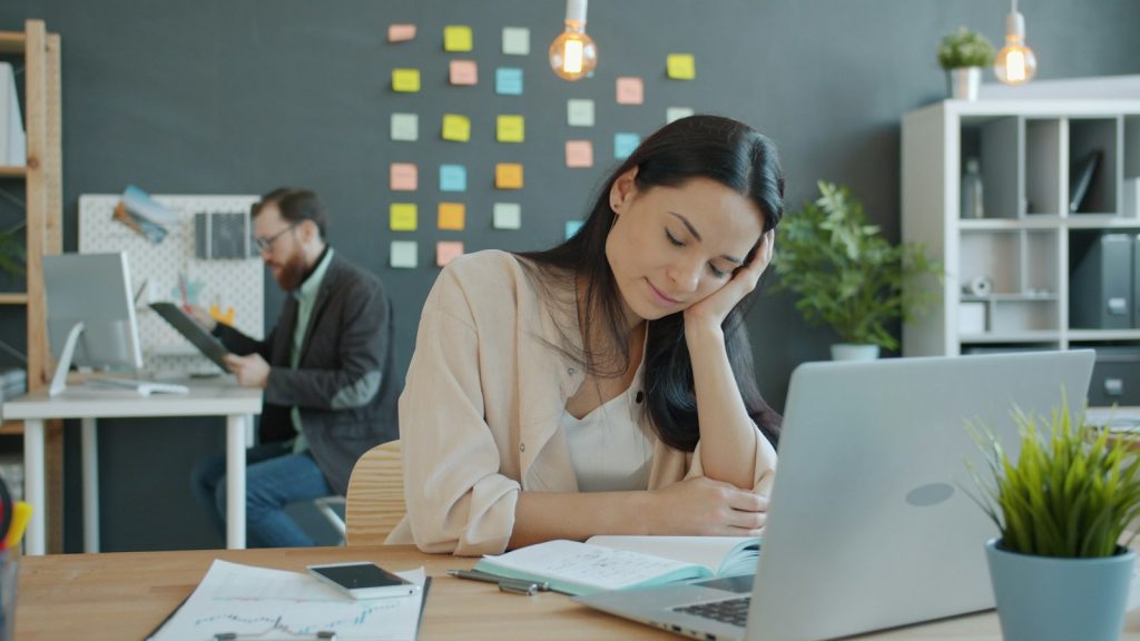 Woman resting her head on her hand at an office desk while coping with divorce at work