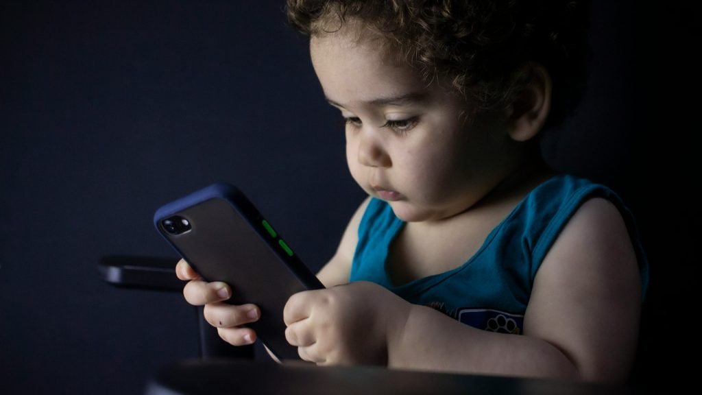 Boy holding his first smartphone and looking at the screen