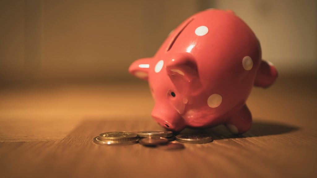 Pink piggy bank on a wooden table, a symbol of allowance for kids and saving
