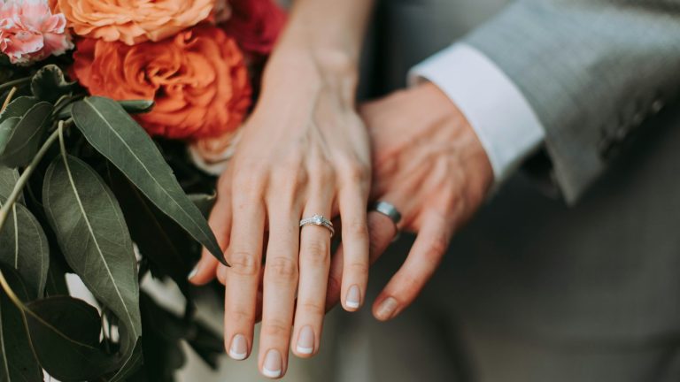 Couple wearing wedding rings holding hands, representing interfaith marriage