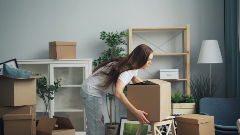 Parent packing moving boxes in a living room while relocating after divorce