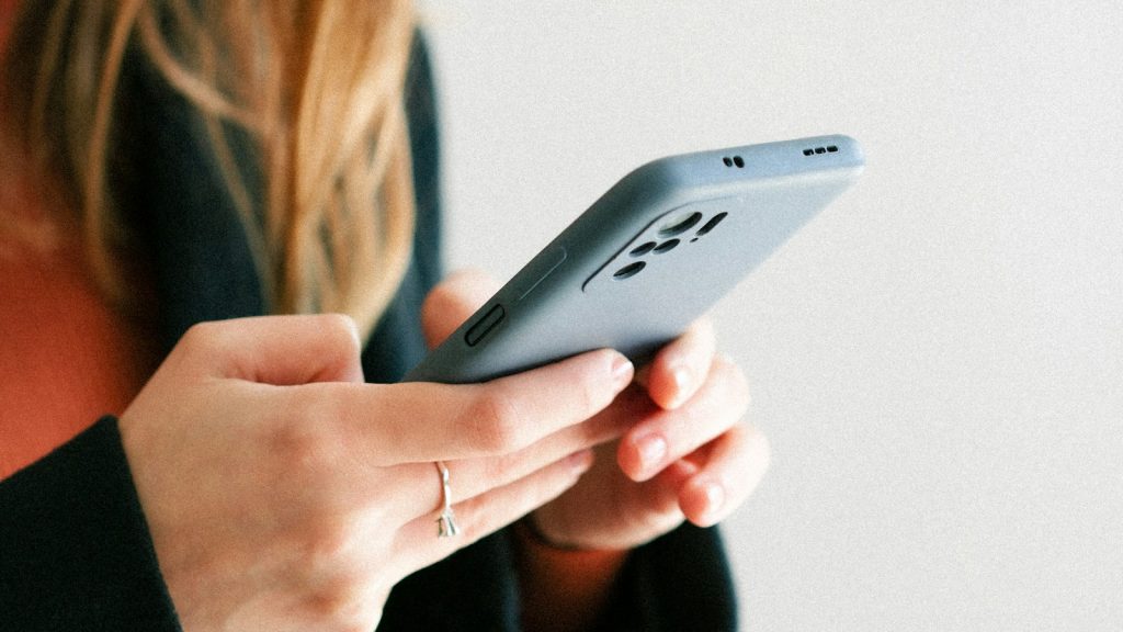 Woman holding a cell phone, thinking twice about social media during divorce