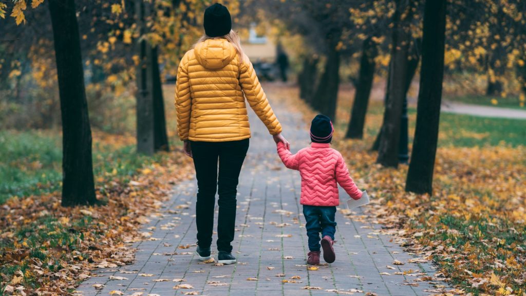Parent holding a child's hand on a path, staying steady while co-parenting with a narcissist