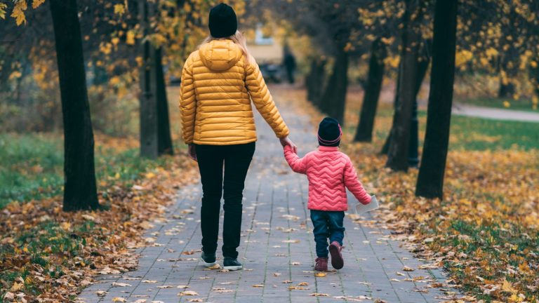 Parent holding a child's hand on a path, staying steady while co-parenting with a narcissist