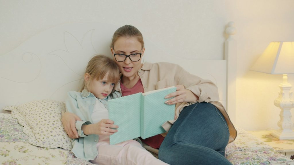Parent reading a story to a young girl to prevent bedtime battles
