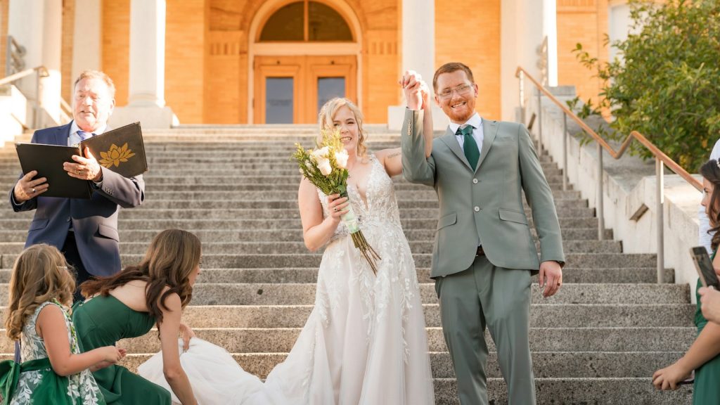 Bride and groom holding hands on stone steps after getting married young